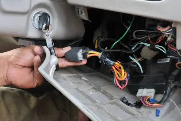 Person removing GPS tracker from car with screwdriver and pliers